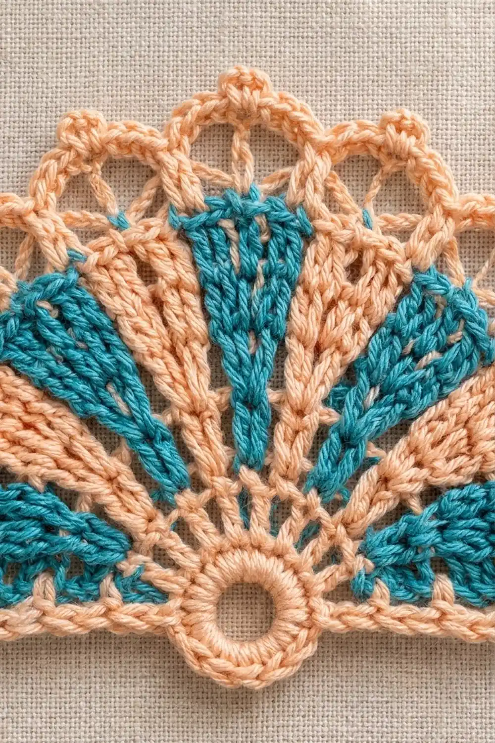 Intricately stitched crochet butterfly in peach with teal accents on neutral linen background.
