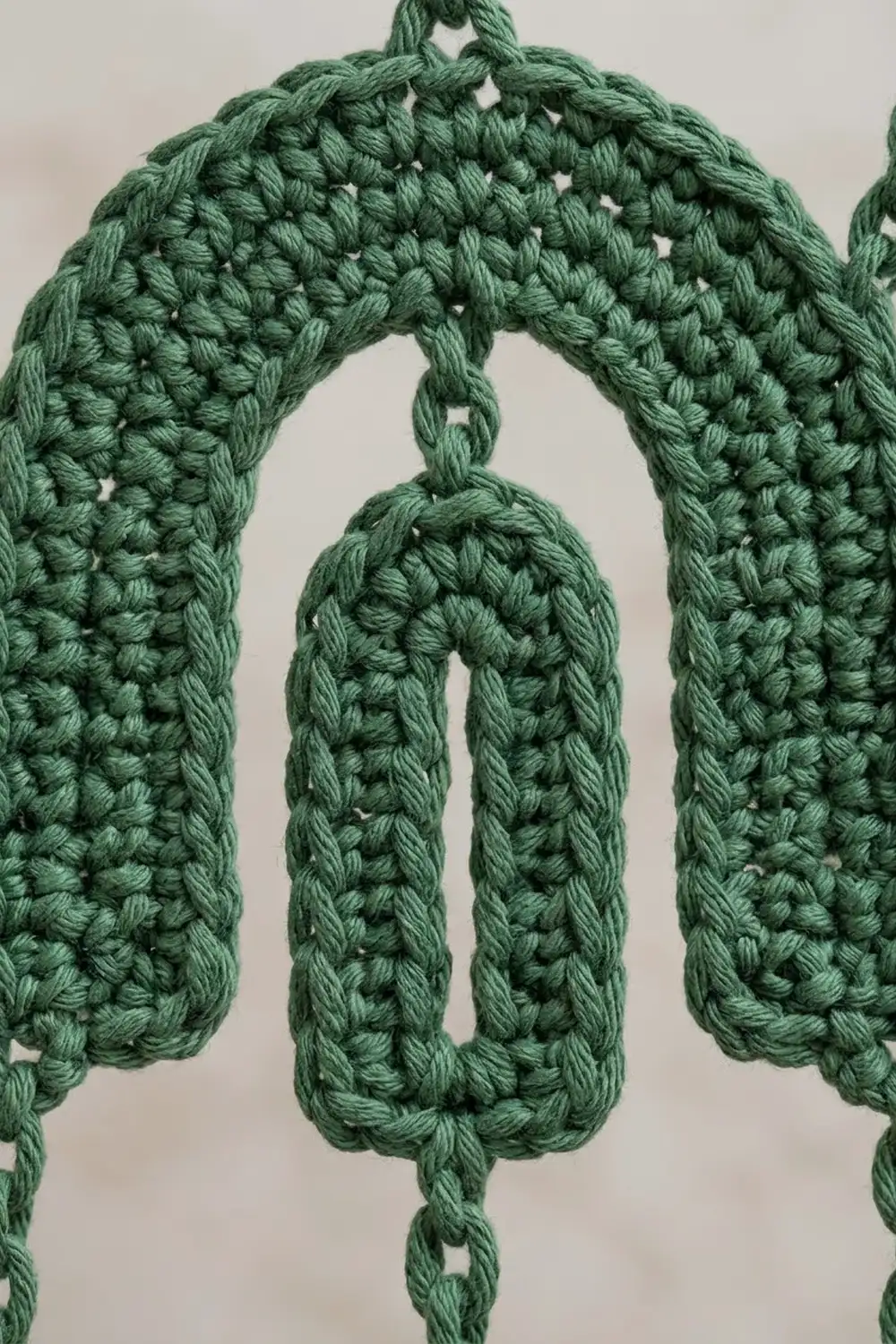Close-up of sage green crochet with textured bobble stitch pattern creating dimensional, lacy detail.