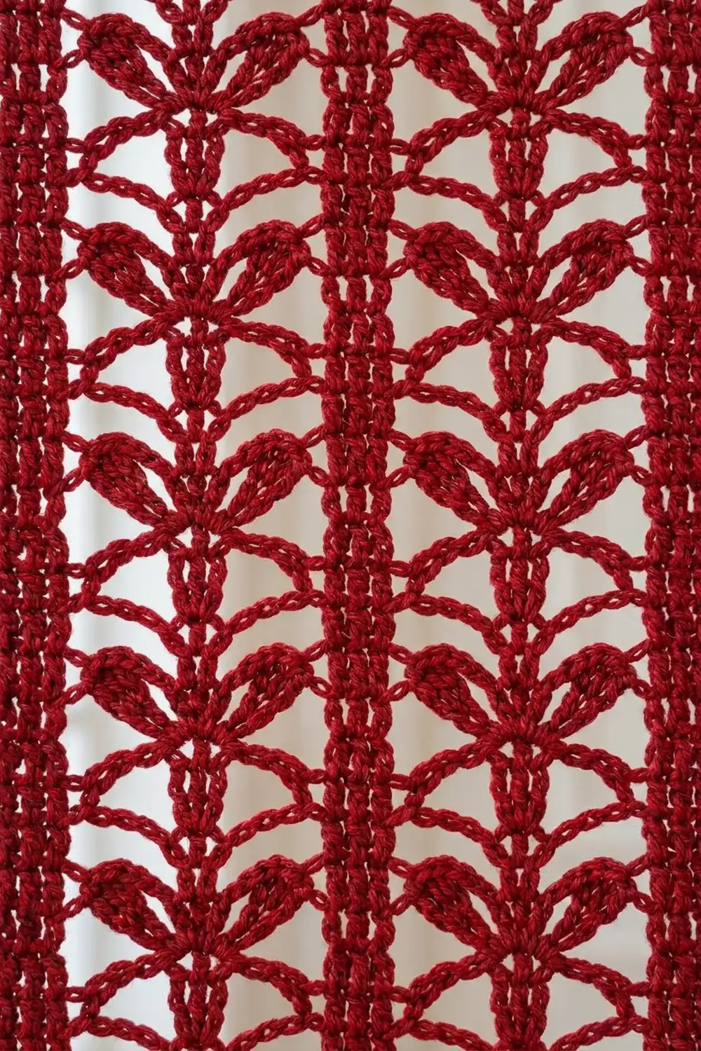 Deep red crocheted lace featuring repeating fan-shell motifs in an intricate openwork geometric pattern.
