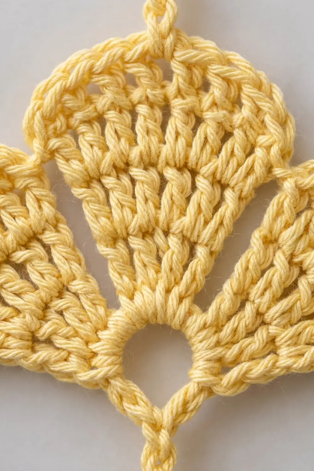Golden-yellow crocheted ornament with a diamond shape and textured stitch detail against a neutral background.