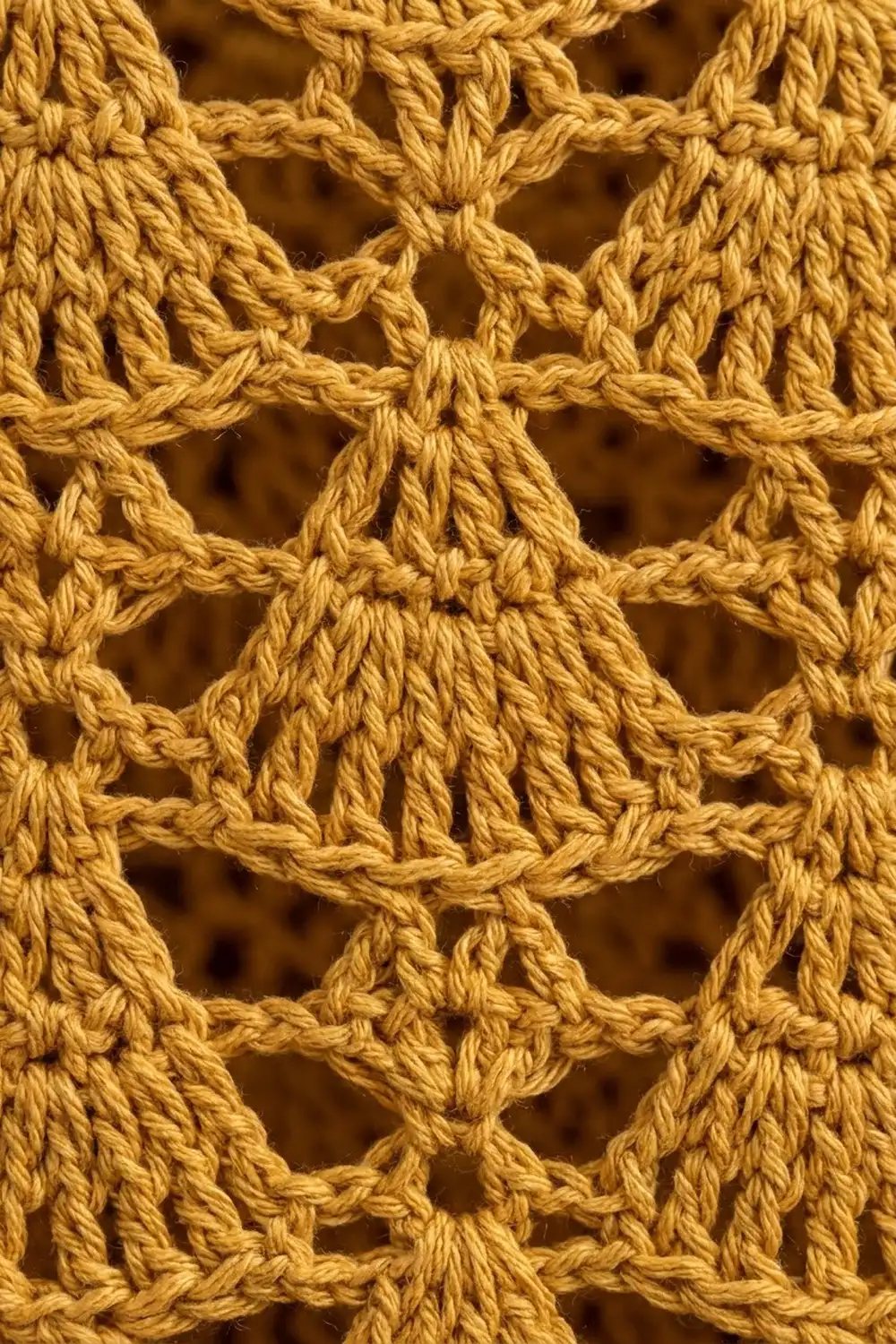 Close-up of golden crocheted lace showing interlocking twisted yarn forming star motifs with open diamond-shaped openings throughout.