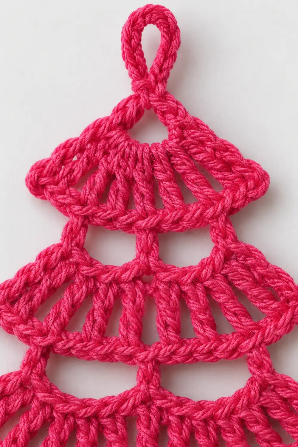 Bright pink crocheted ornament featuring three tiered scalloped sections with a loop for hanging.