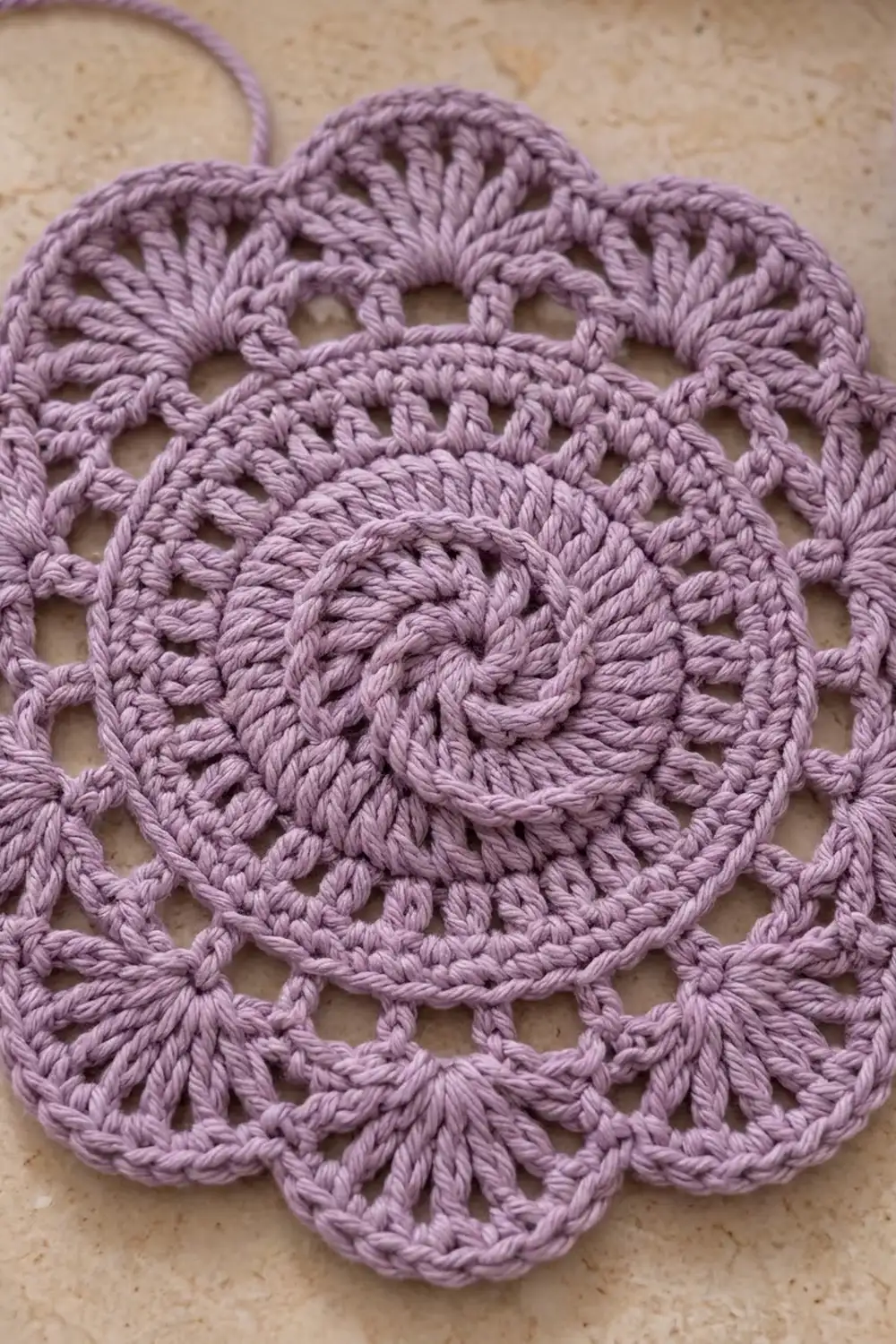 Intricate purple crocheted mandala-style coaster with openwork lace design on beige fabric.