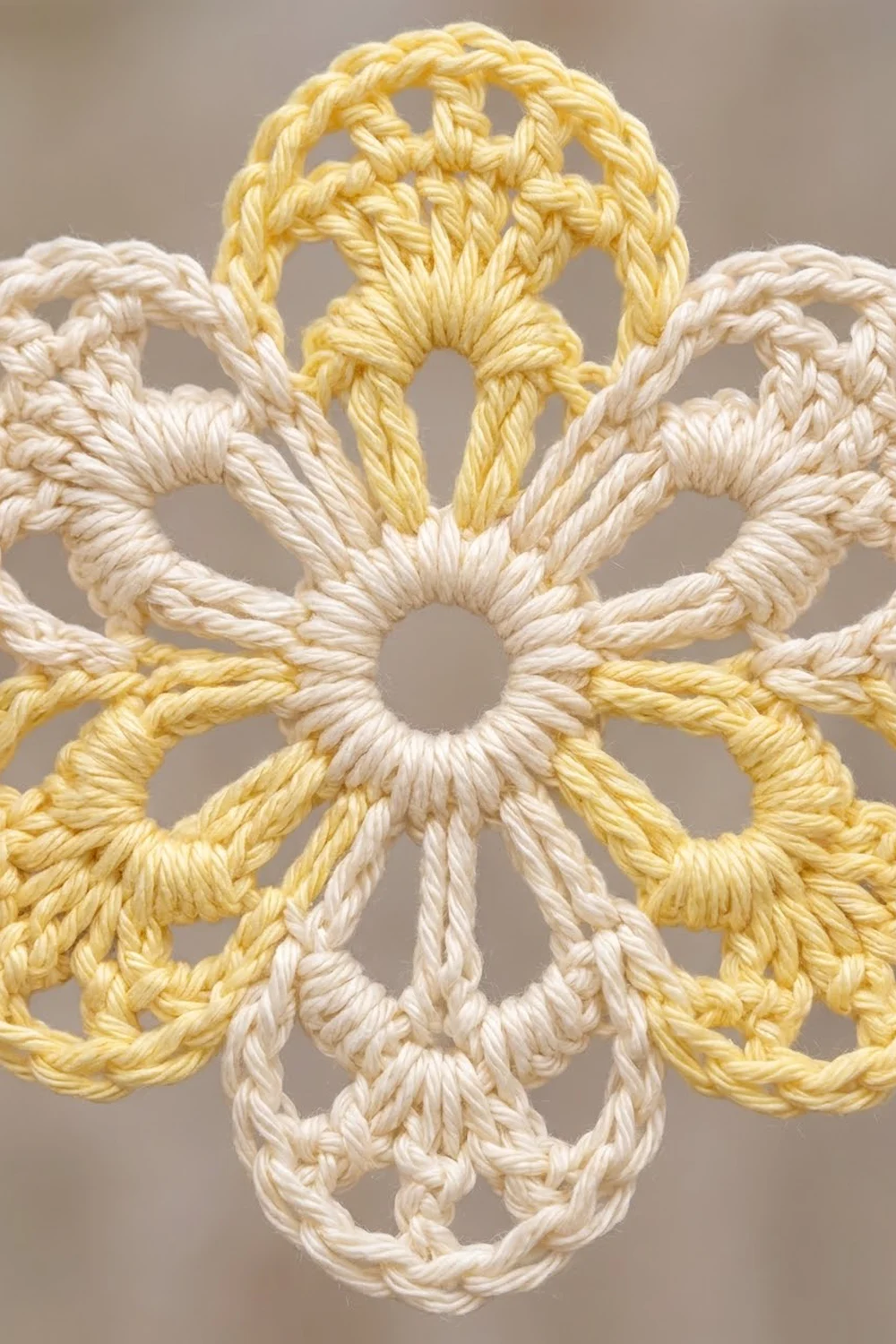 Cream and golden-yellow crocheted geometric pattern with interlocking braided loops and knots on a neutral background.