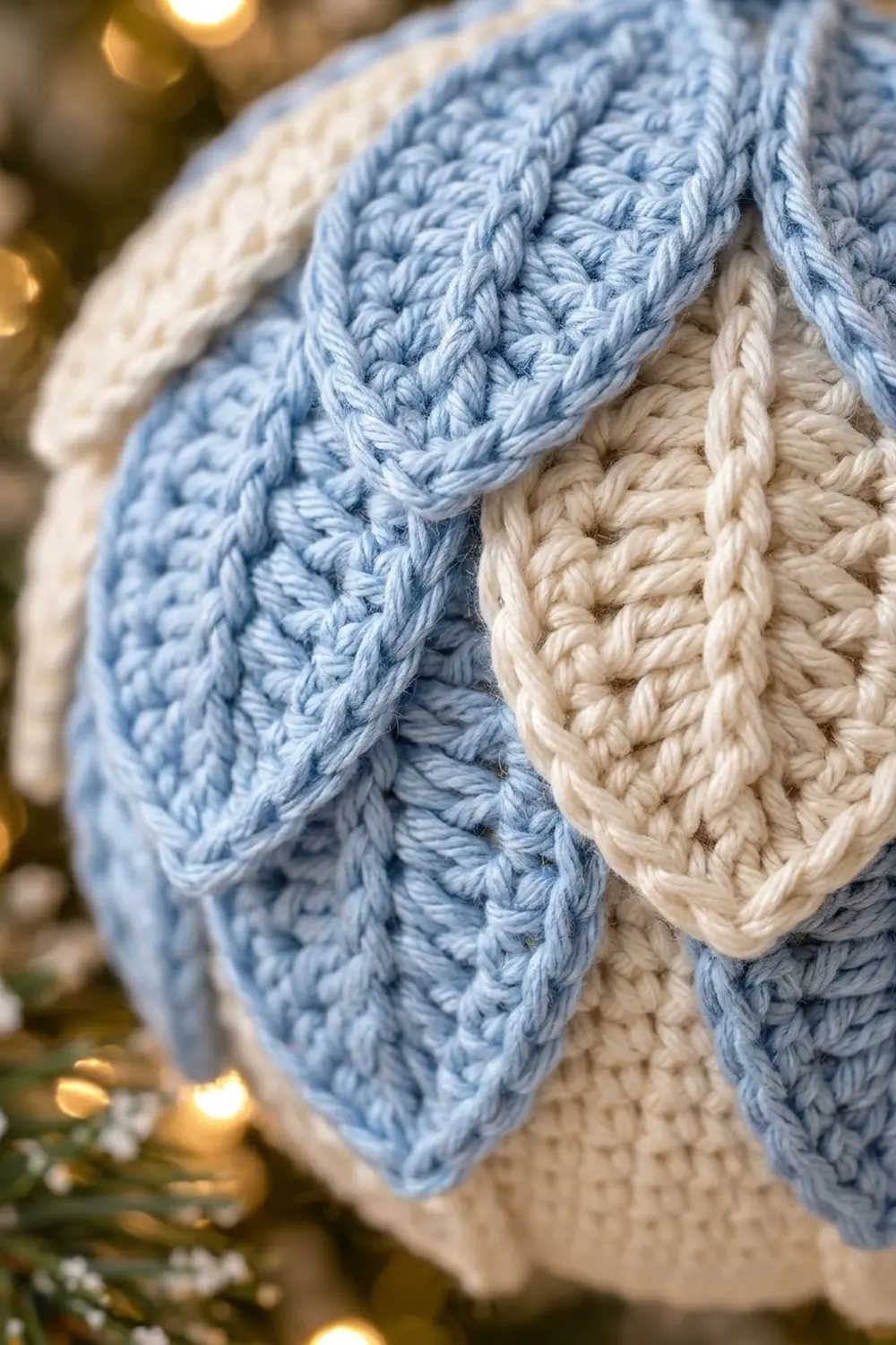Close-up of blue and cream cable-knit fabric showing detailed stitch texture against a warm, blurred background.