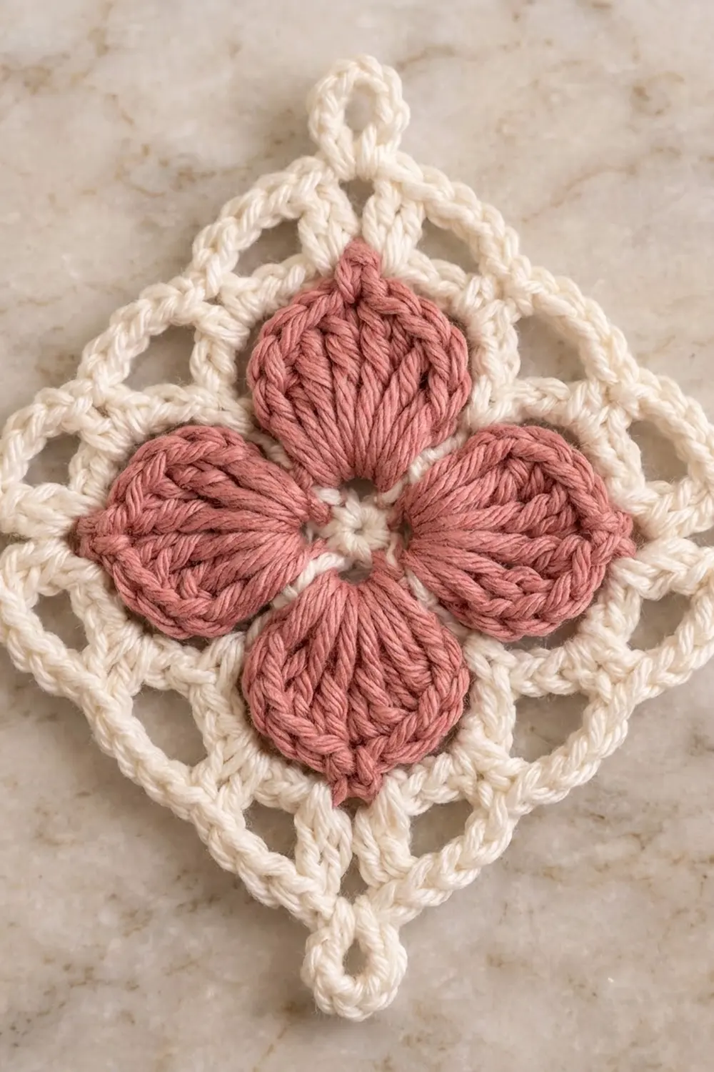 Cream lace crocheted diamond ornament with four dusty-pink bobbles creating a flower center.