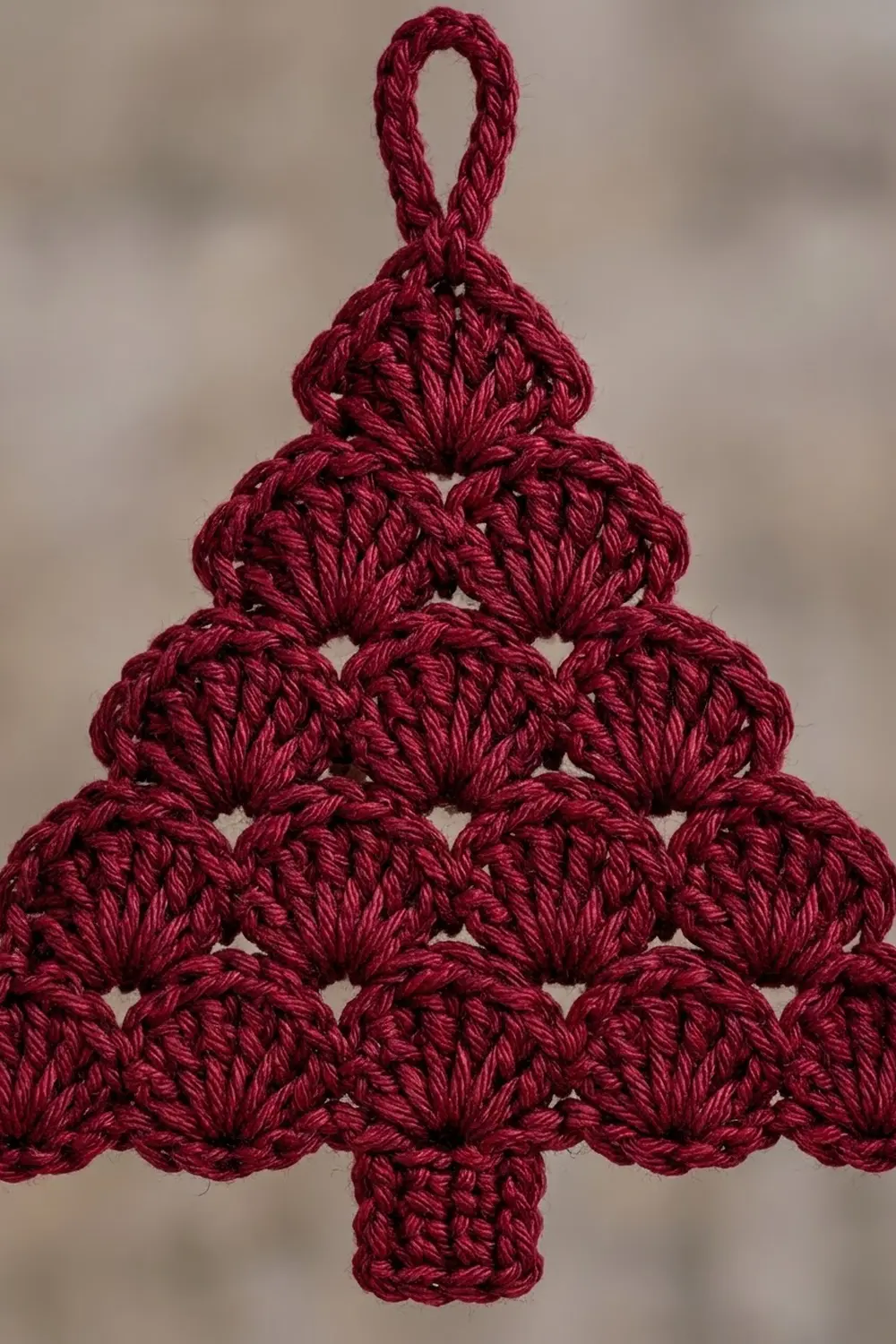 Close-up of deep red crocheted spheres stacked in a Christmas tree shape with a hanging loop detail.