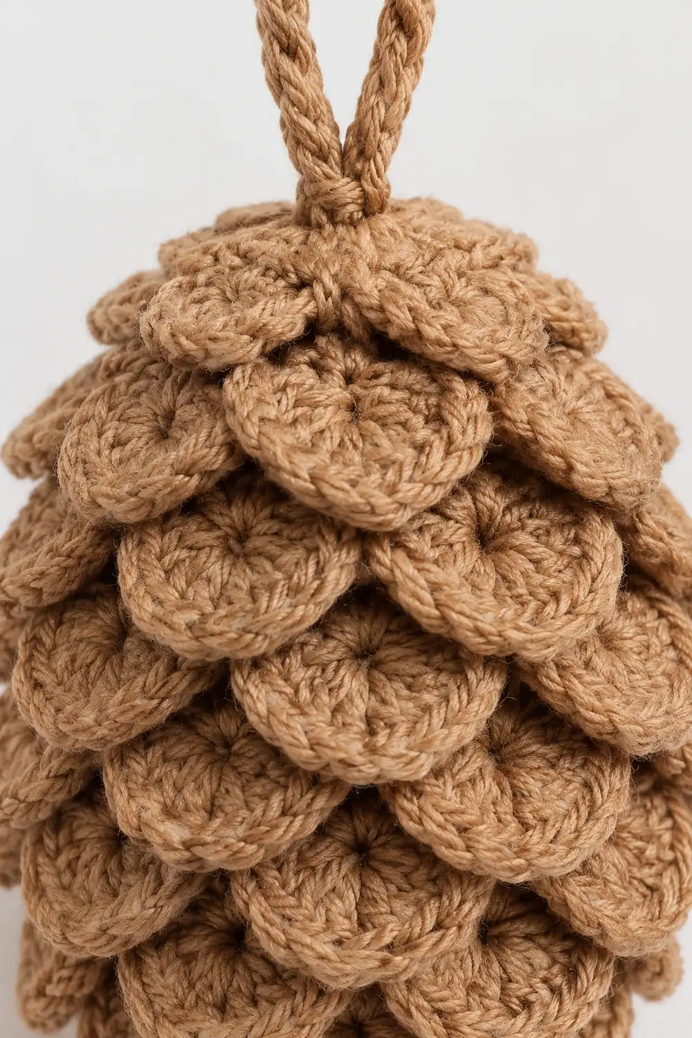 Close-up of a decorative rope ornament made from tightly coiled jute twine in a pine cone shape.
