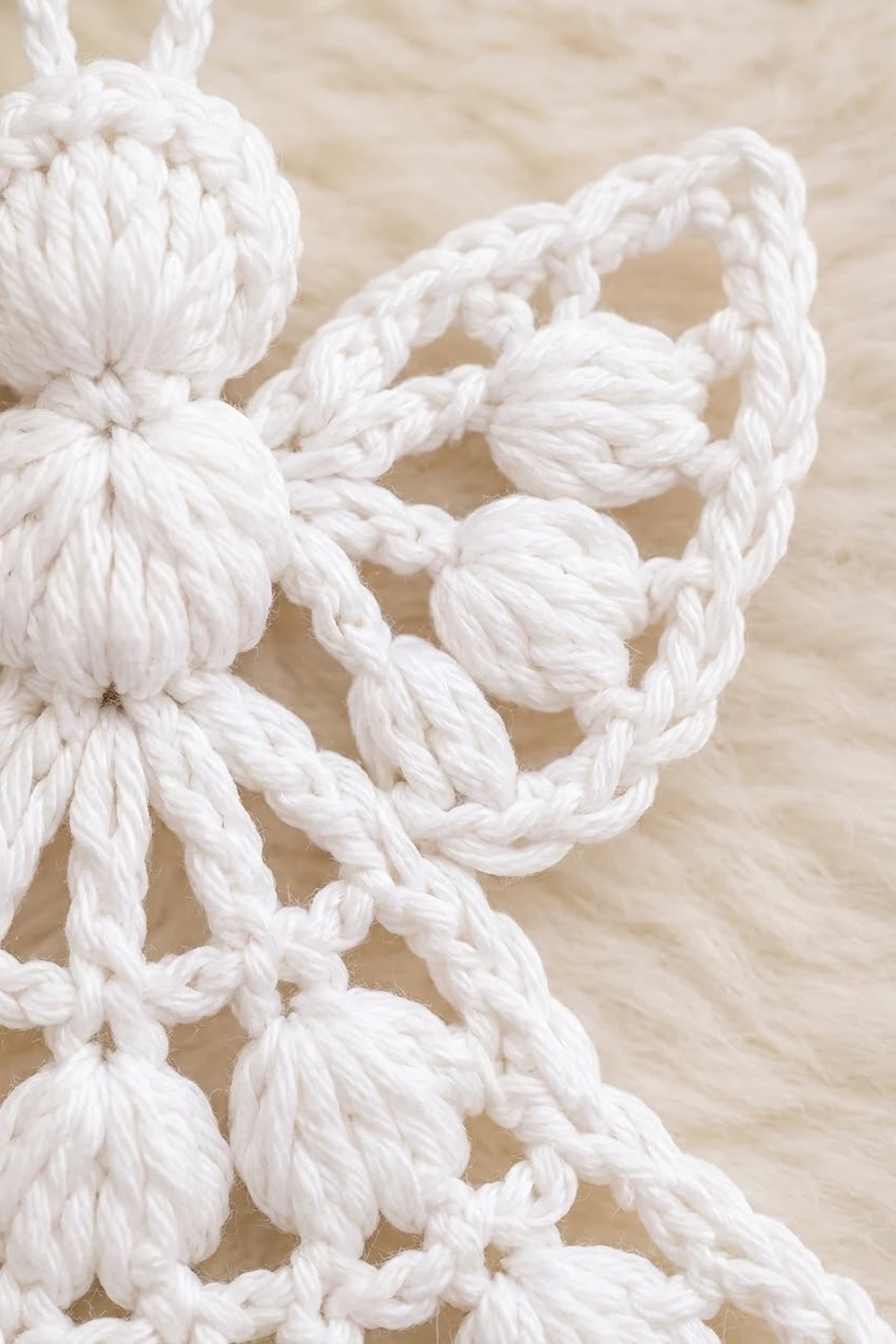 White crochet with dimensional puff stitches and bobbles displayed on a natural beige linen background.
