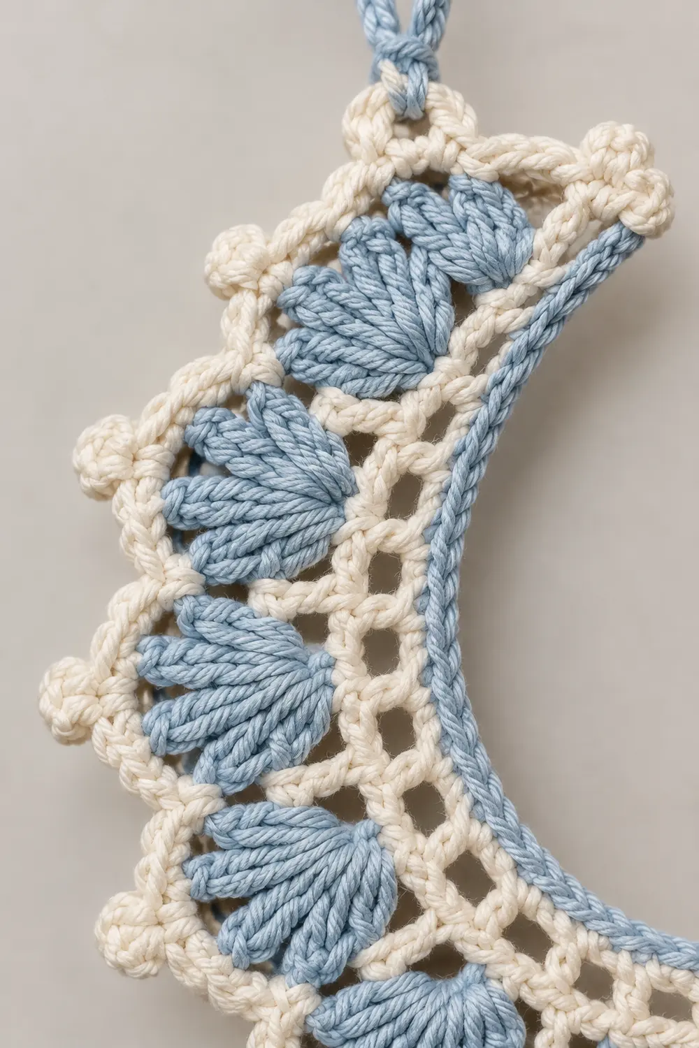 Close-up of decorative macramé trim featuring blue and cream twisted rope with knotted fringe detail.