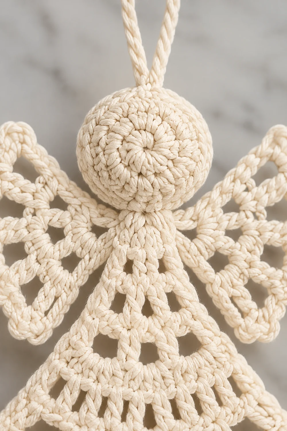 Handmade macramé angel ornament with knotted cream-colored rope, featuring a spherical head and outstretched wing details.