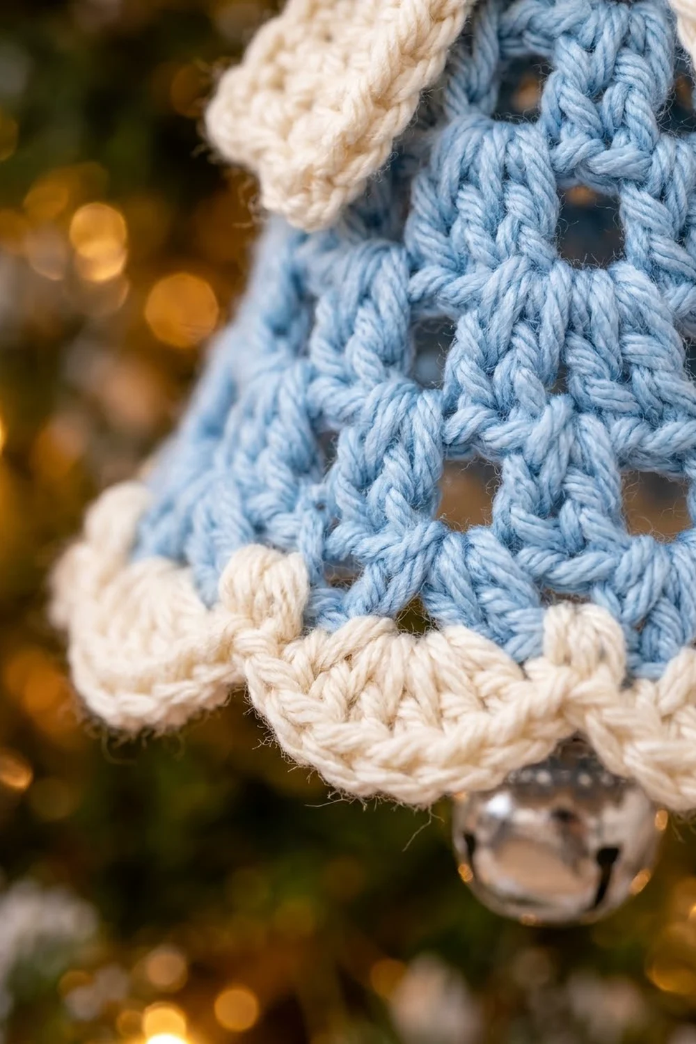 Handmade crochet fabric in slate blue and cream with open lattice stitching against warm bokeh backdrop.