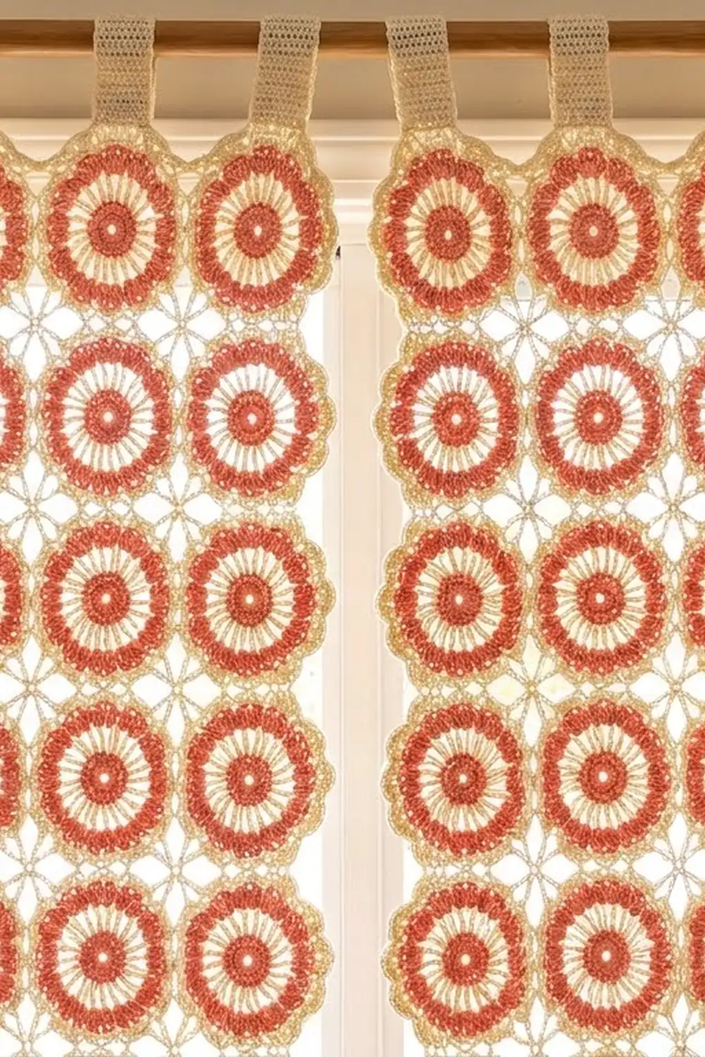 Red and cream crocheted lace curtain featuring circular medallion motifs, hanging from a wooden rod.