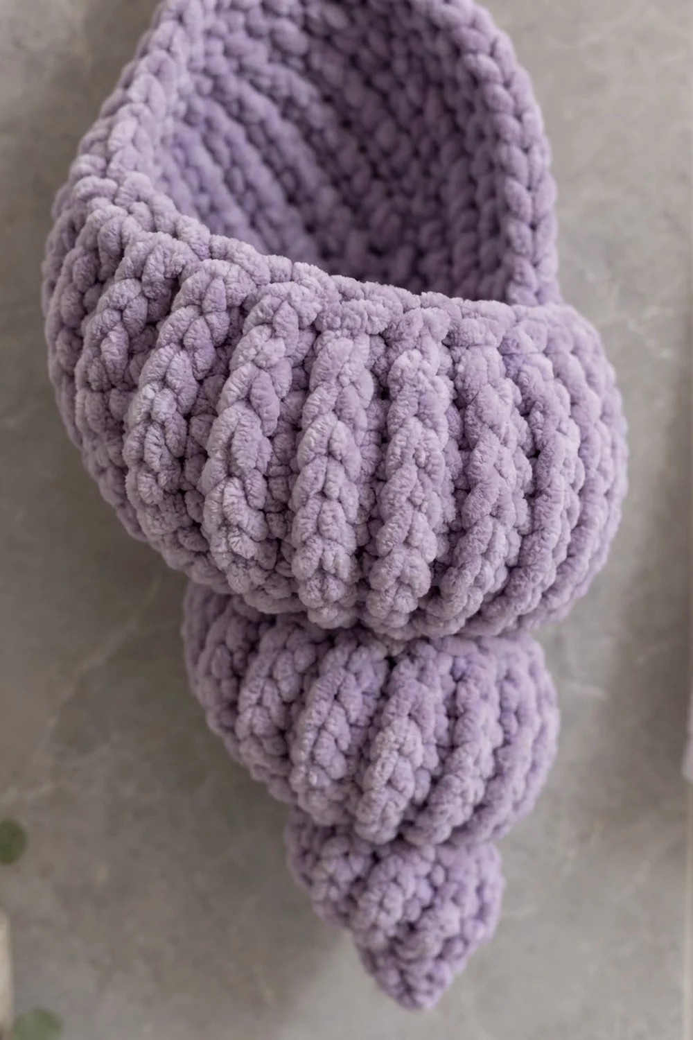 Lavender crocheted item with raised bobble stitches creating dimensional texture against a neutral background.