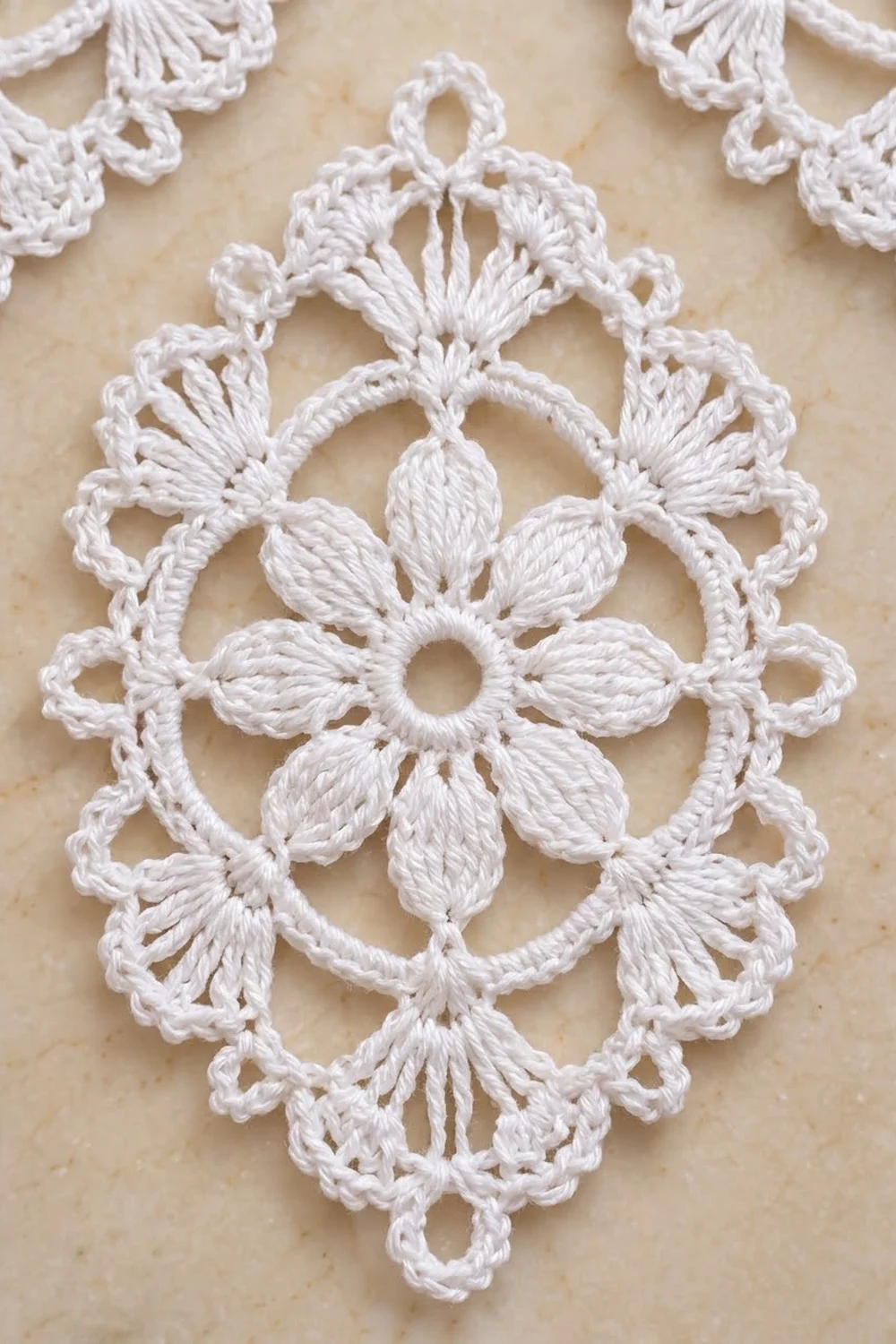 White crocheted lace doily with intricate snowflake medallion pattern on a cream background.