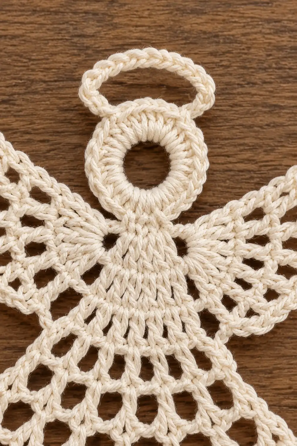 Handmade macramé angel ornament with braided rope halo and wings on wooden background.