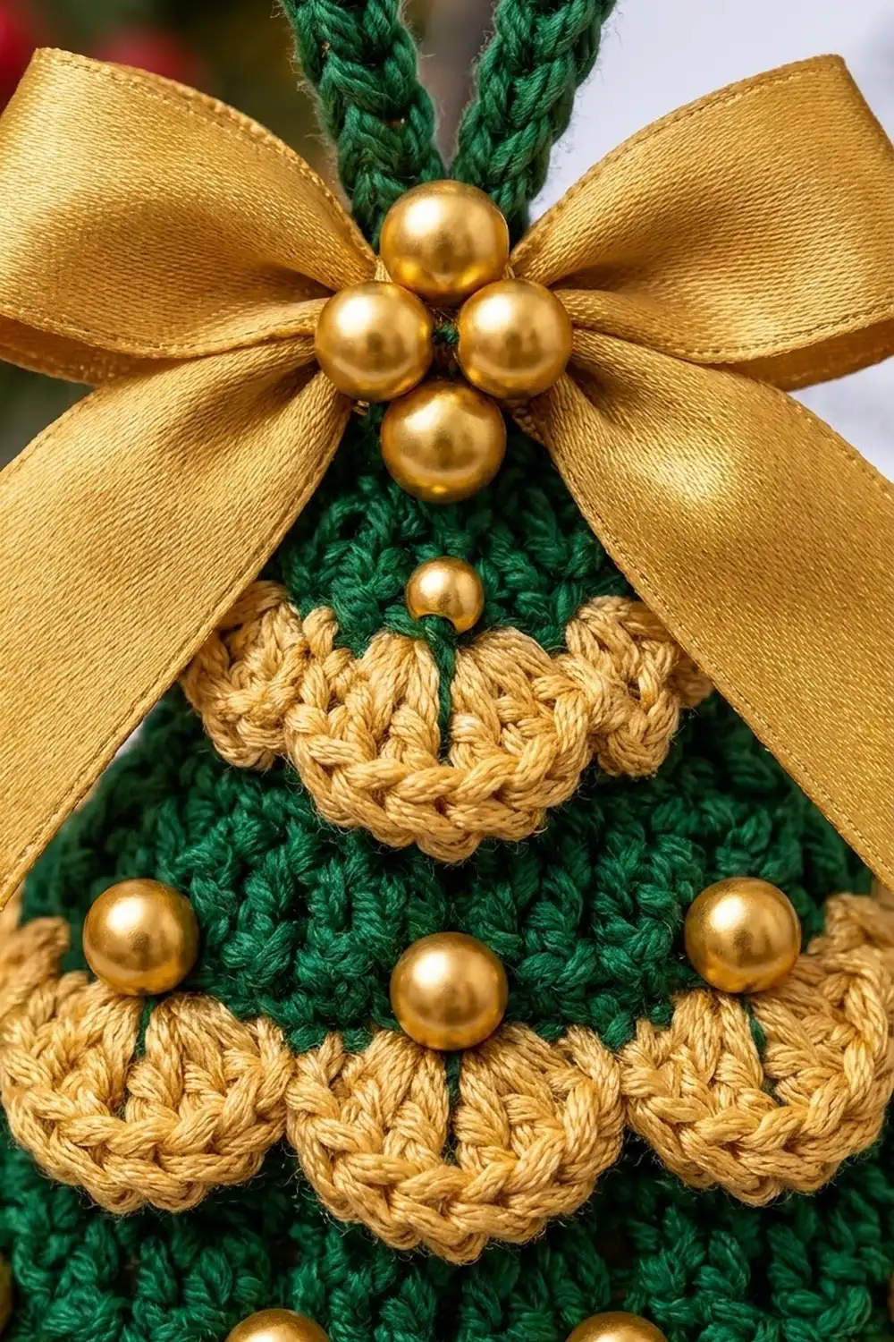 Crocheted green wreath with golden pearl beads, ribbon bow, and scalloped tan trim.