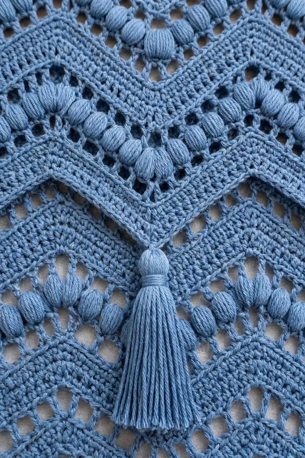 Light blue crochet lace displaying geometric diamond openwork with dimensionally textured knot embellishments throughout.