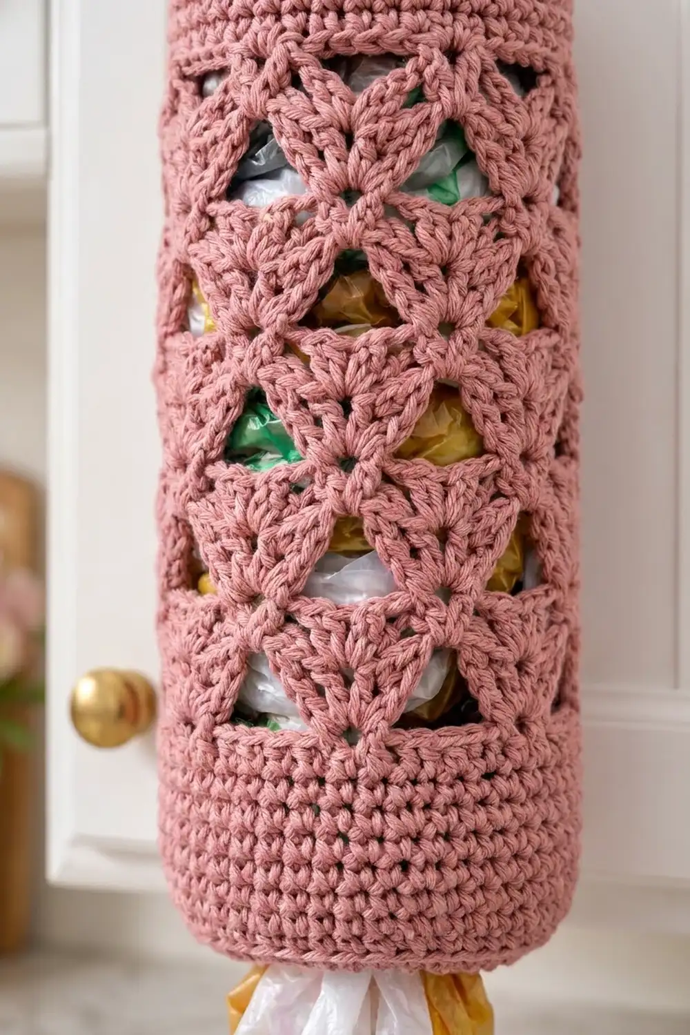 Mauve crochet tube with ornamental openings displaying colorful Christmas ornaments in green, white, and gold.