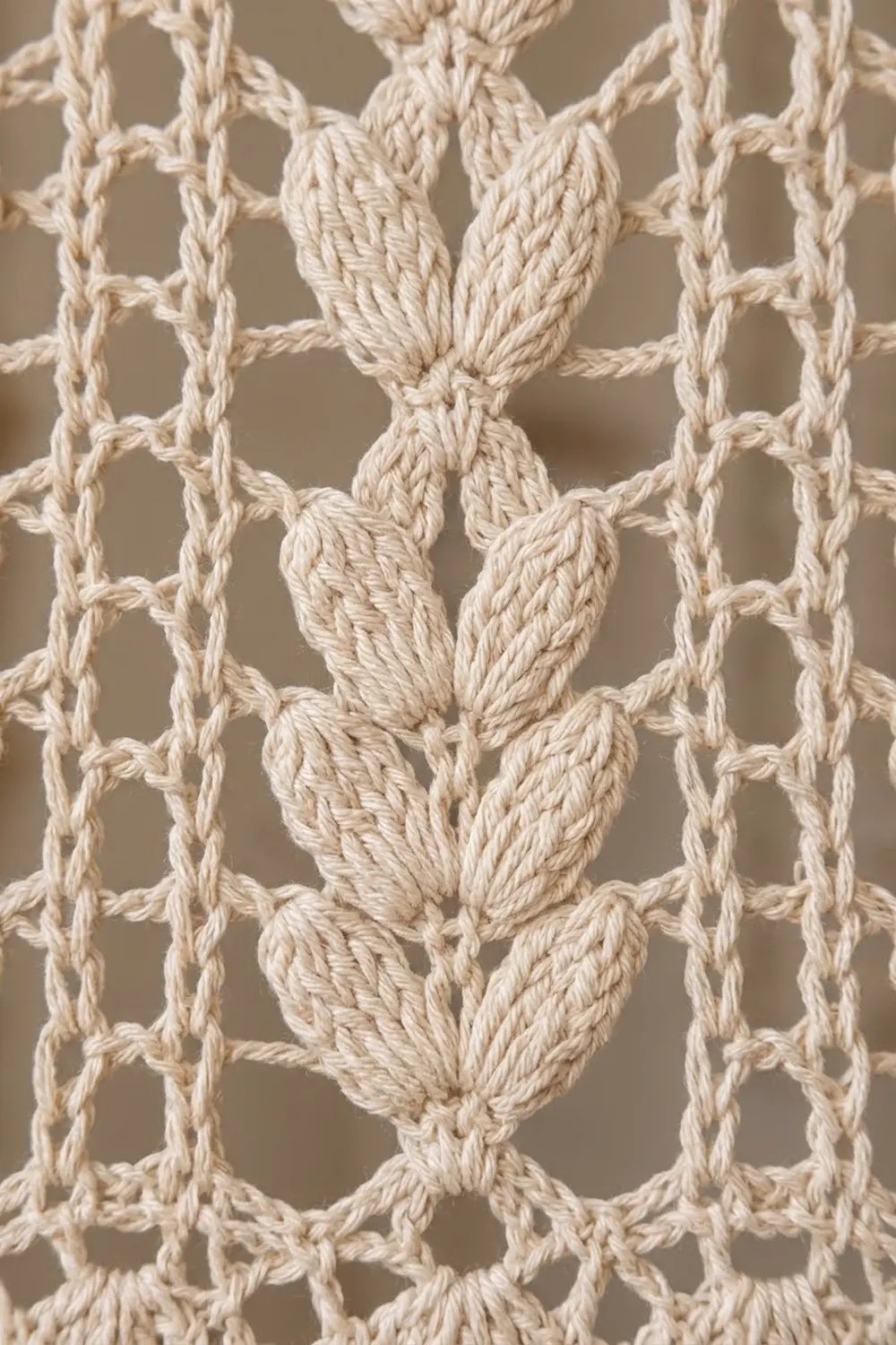 Cream-colored crochet with an openwork lattice pattern featuring decorative leaf motifs and twisted rope strands.