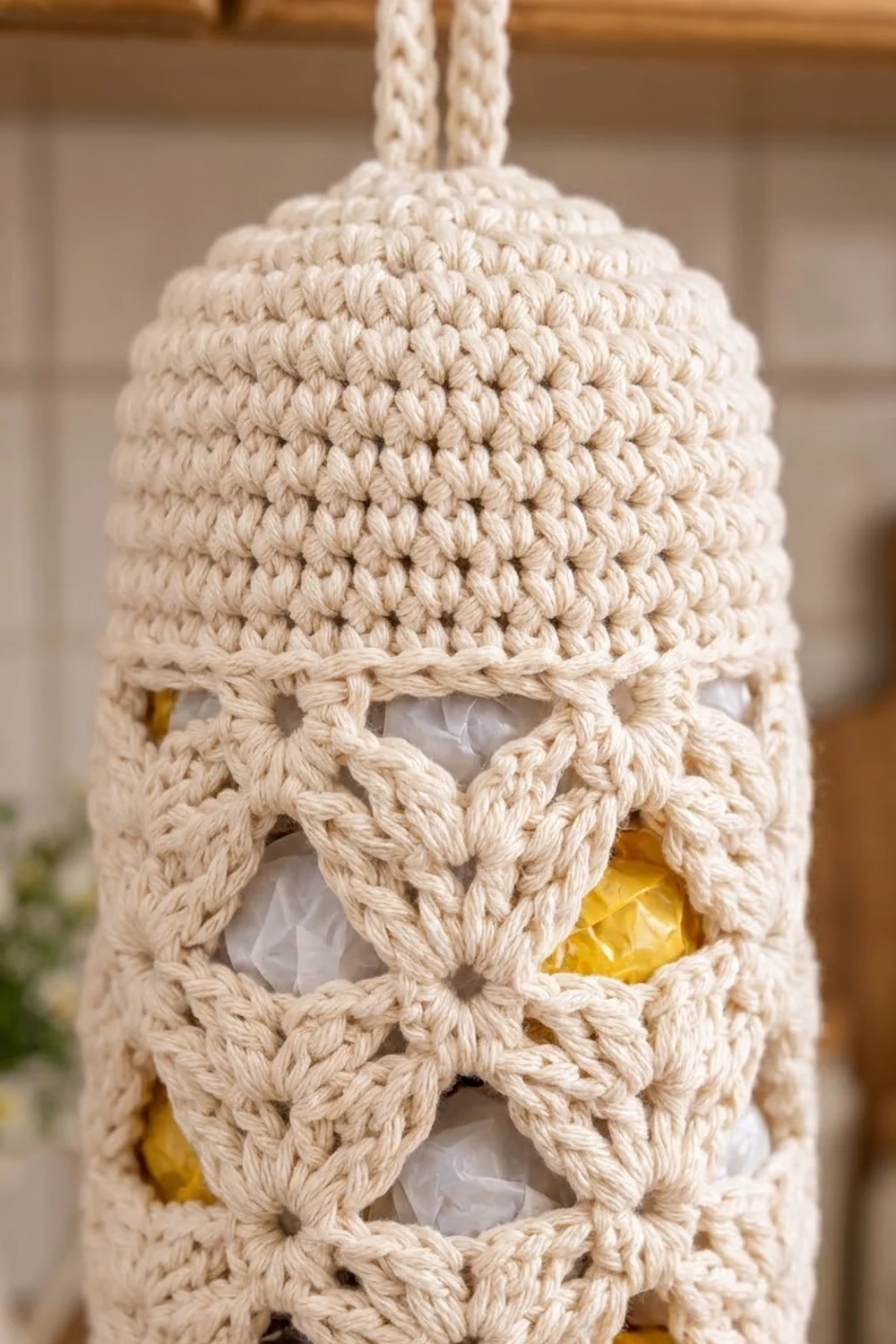 Cream crochet hanging organizer with densely stitched top and open diamond-pattern cutouts revealing yellow items through white mesh.