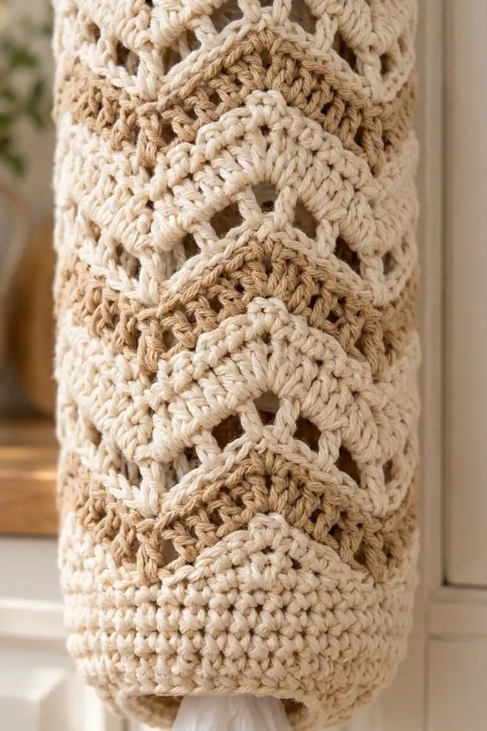 Close-up of alternating cream and tan crocheted fabric with openwork stitches and textured pattern.