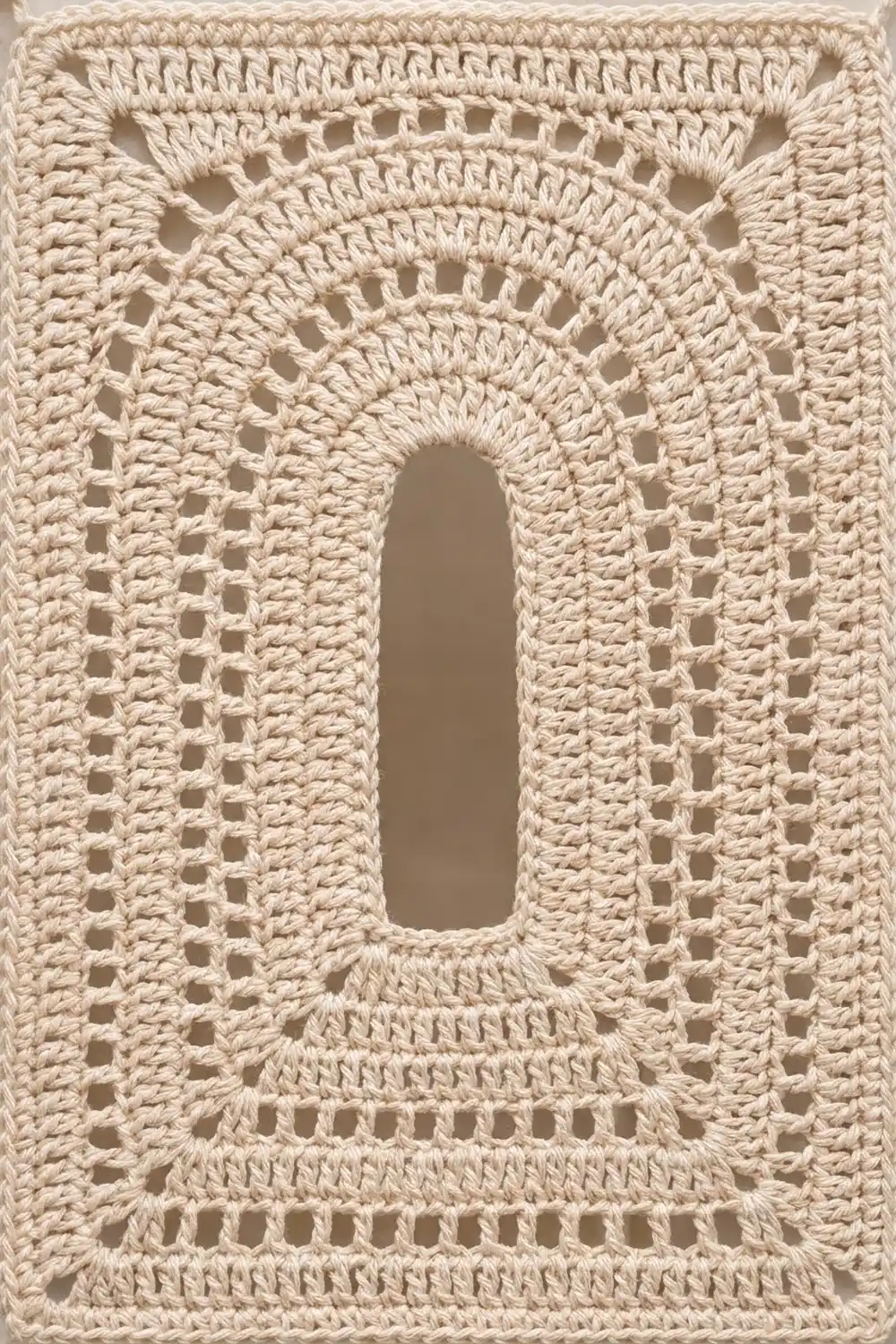 Close-up of cream-colored crochet with open lace pattern and rectangular cutouts surrounding a large oval center opening.