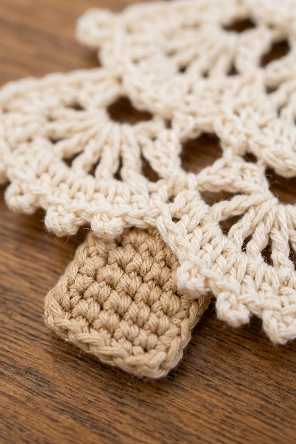 Intricately stitched cream and tan crochet with delicate open lacework displayed on a warm wooden surface.