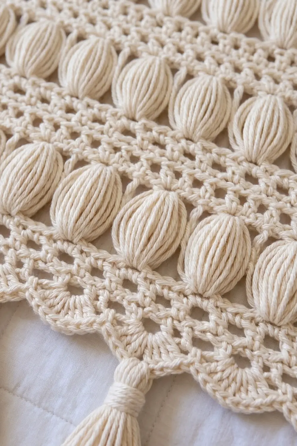 Cream crocheted lace and ivory yarn balls arranged on white linen, highlighting handmade textile craftsmanship and detail work.