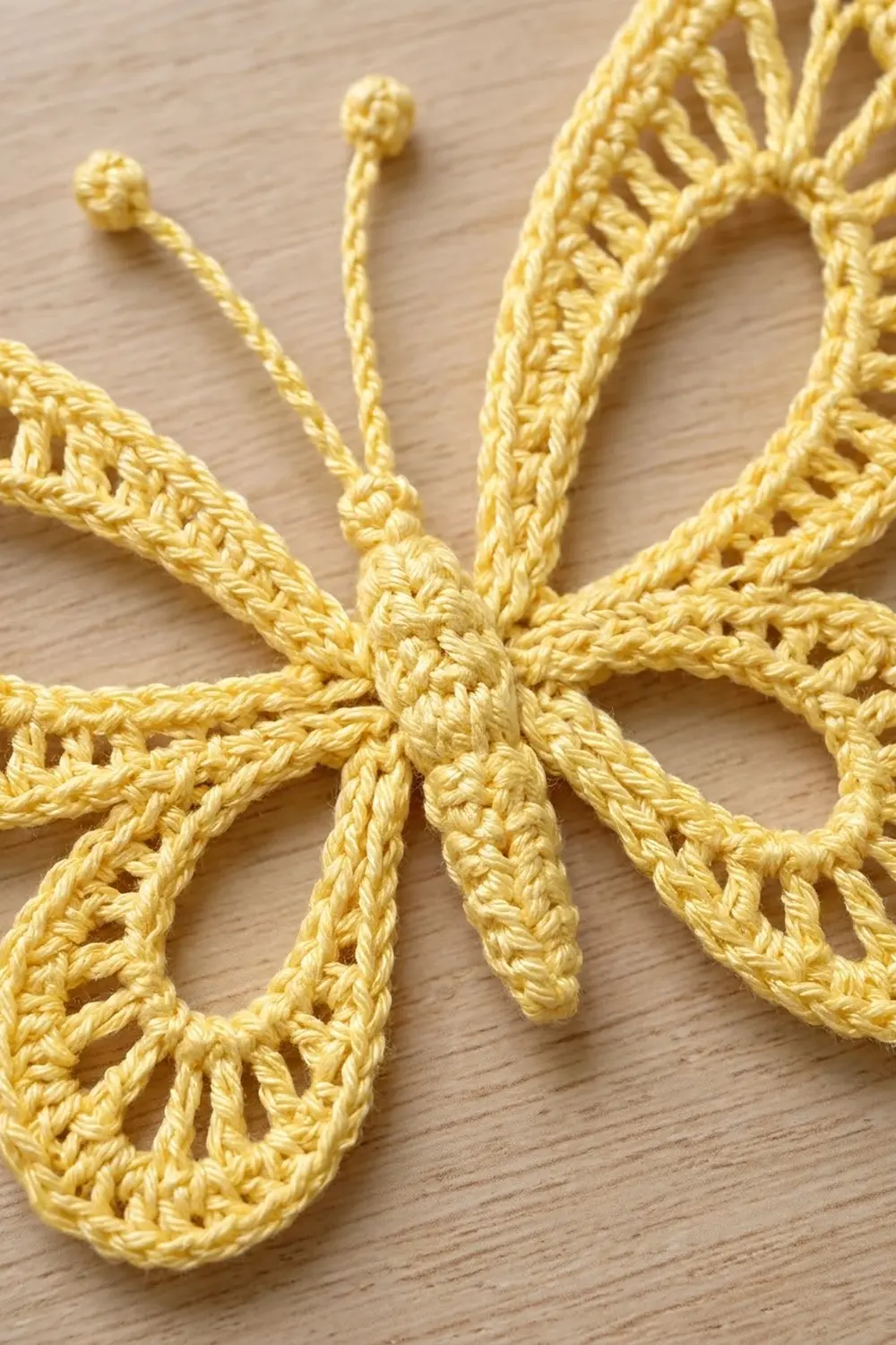 Bright yellow crocheted sea stars with delicate antenna-like tendrils on a light wooden surface.