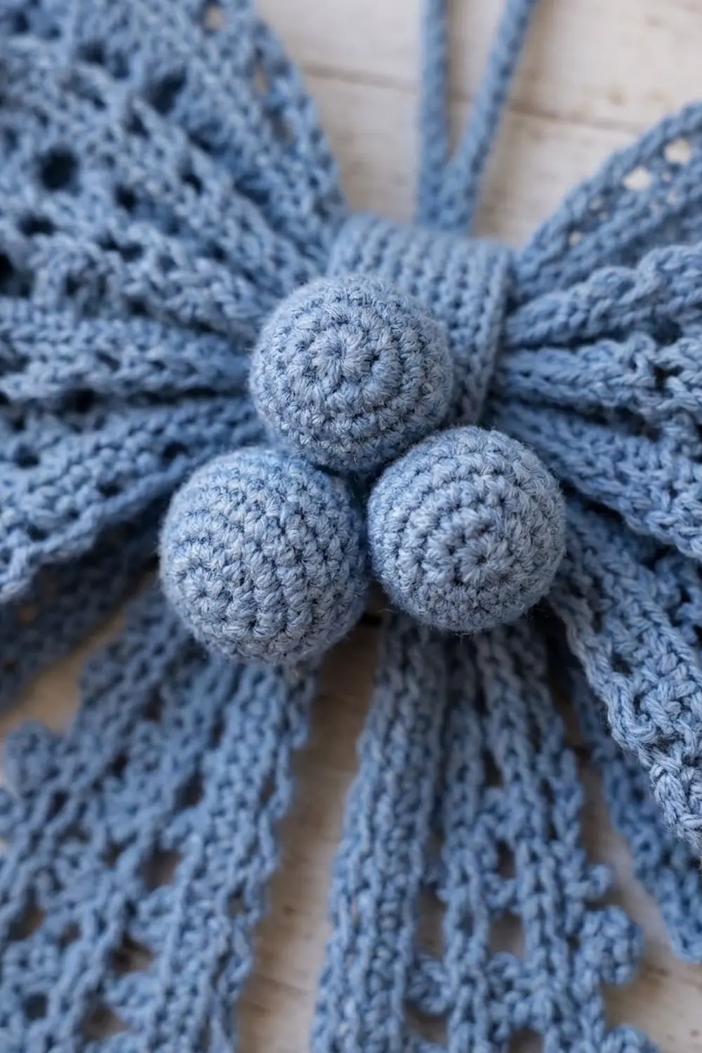 Three periwinkle crocheted balls clustered on lacy blue crochet fabric.