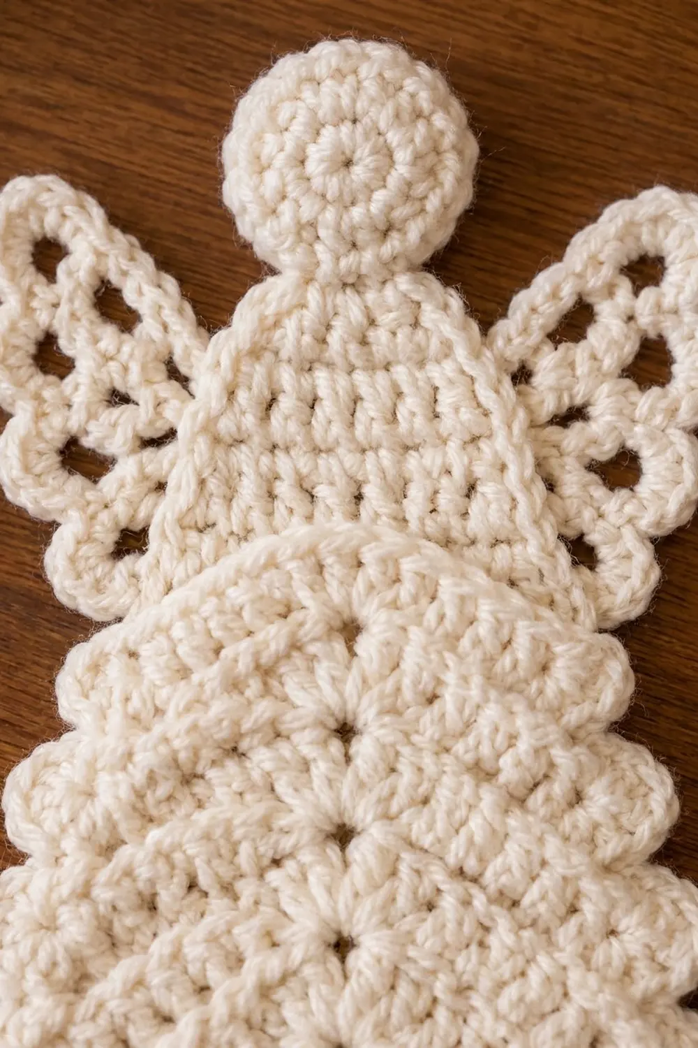 Close-up of cream-colored crocheted octopus toy with bumpy texture and wavy arms on dark wood surface.