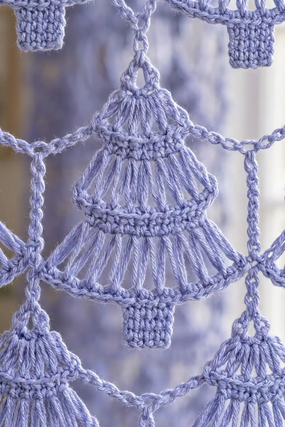 Lavender macramé hanging with connected shell-shaped bells and intricately knotted chains forming a decorative garland.