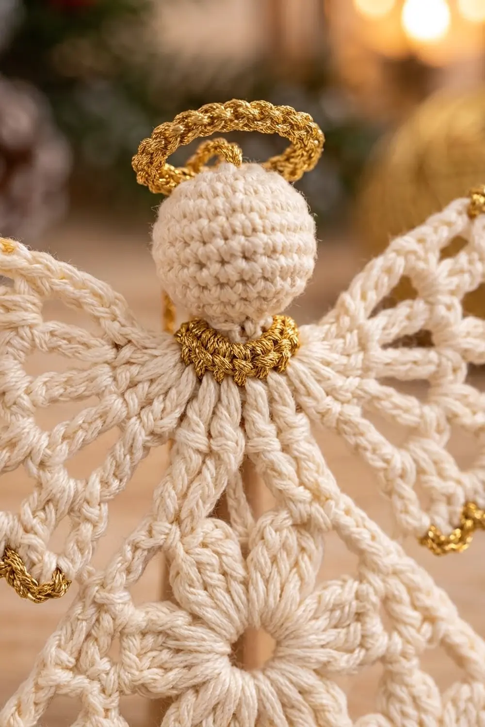 Crocheted angel ornament with cream-white body, textured robe, and gold metallic halo on soft, bokeh background.