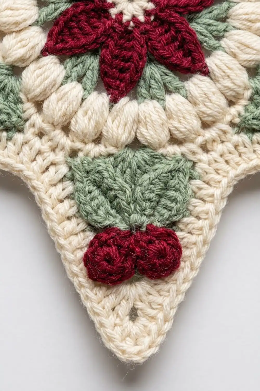 Close-up of crocheted strawberries with deep burgundy berries and sage-green leaves on cream background.