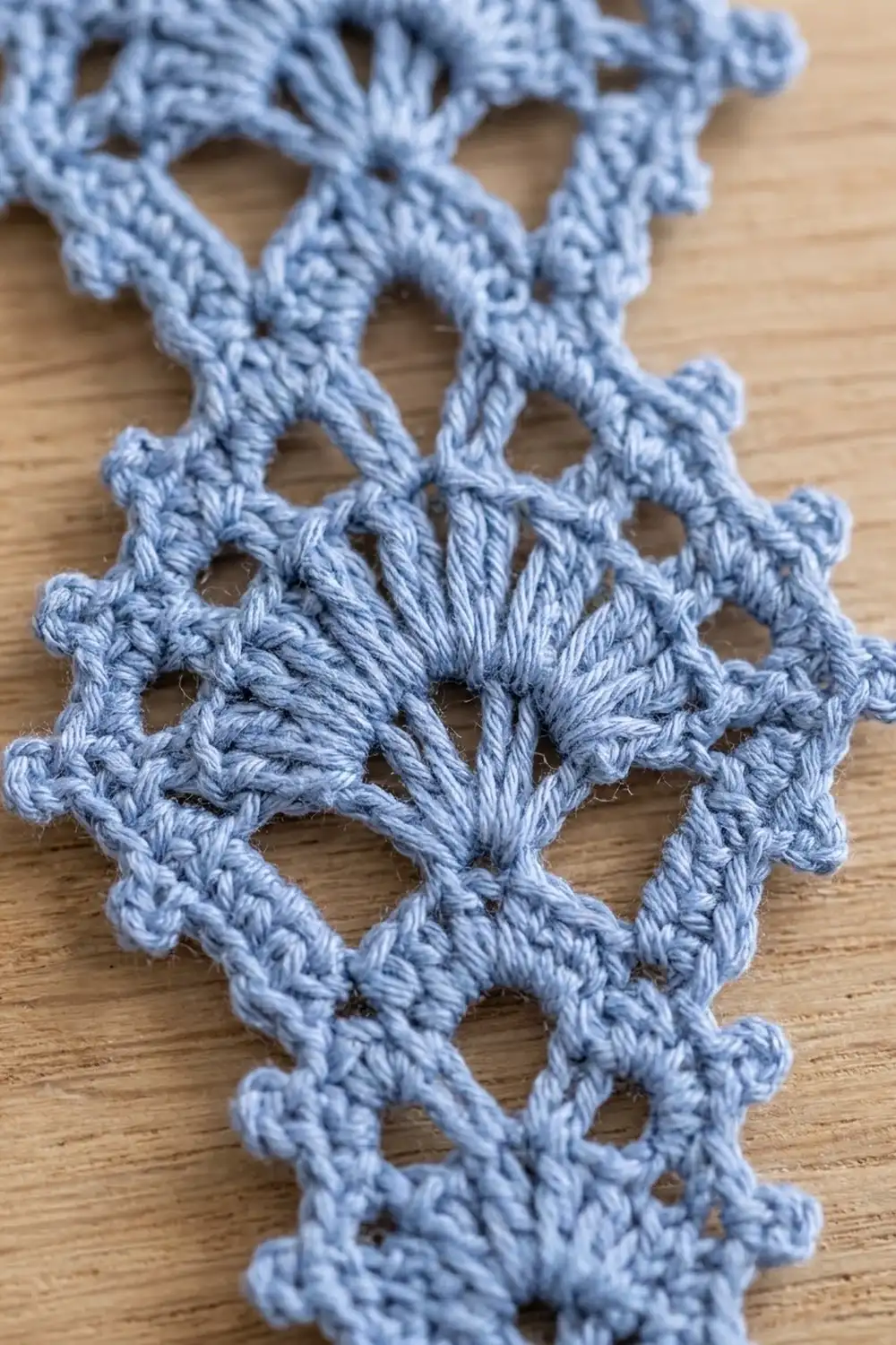 Periwinkle crochet lace with delicate openwork design resting on natural wood.
