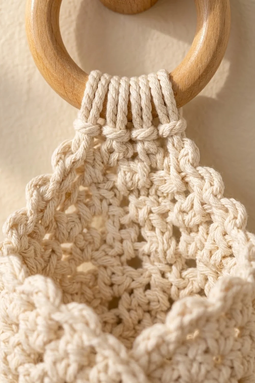 Natural wood ring topped macramé wall hanging with cream rope, knotwork, and textured crochet details.