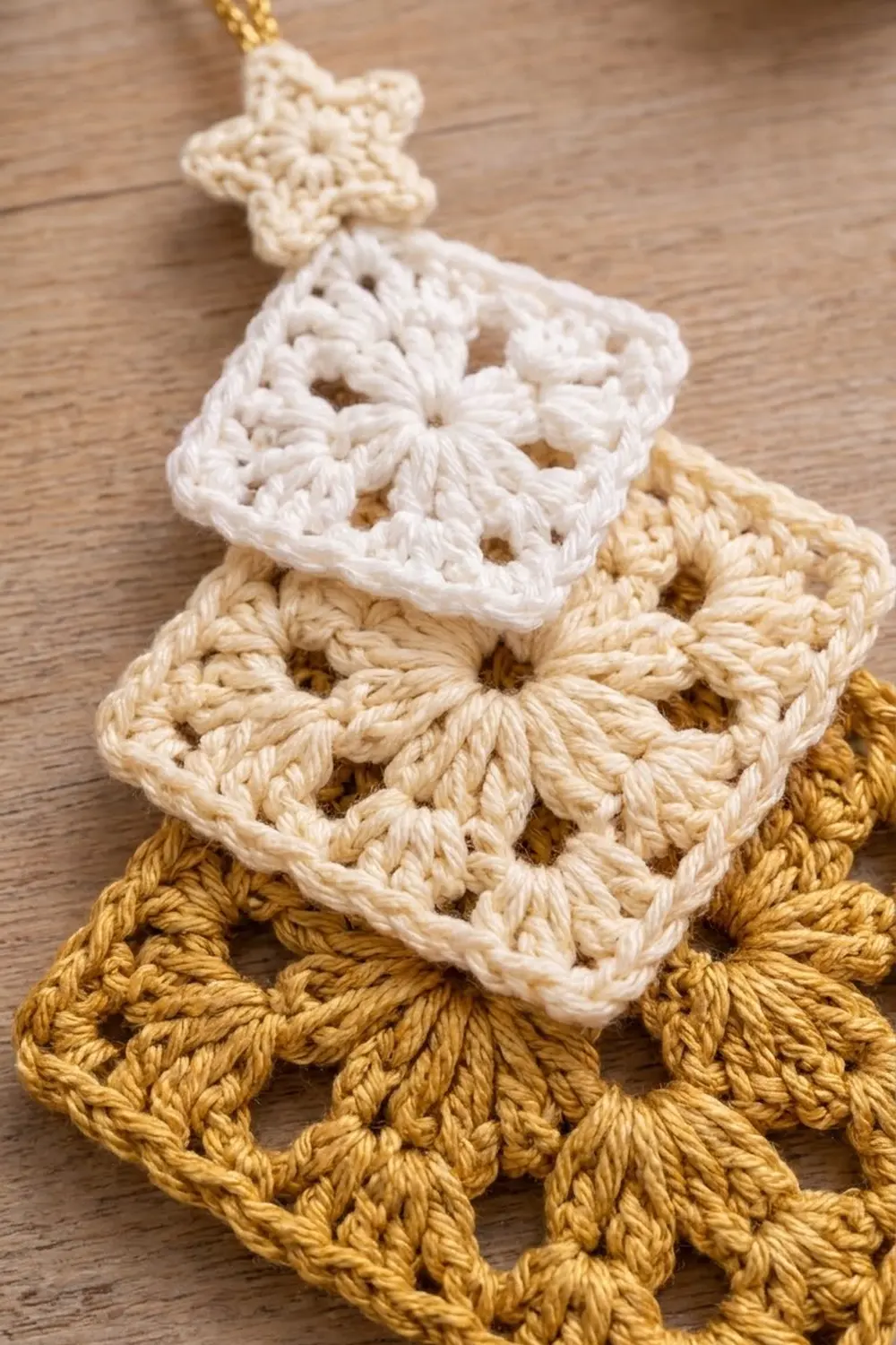 Golden, cream, and white crocheted granny square ornaments with open lacework patterns stacked on warm wood.