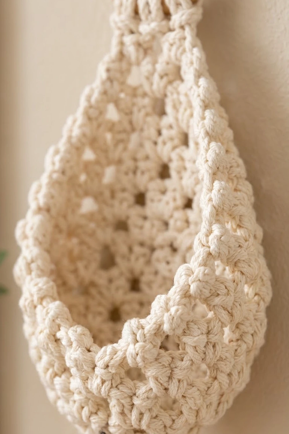 Cream-colored crocheted lace with detailed openwork pattern and textured edge, photographed against a warm neutral background.