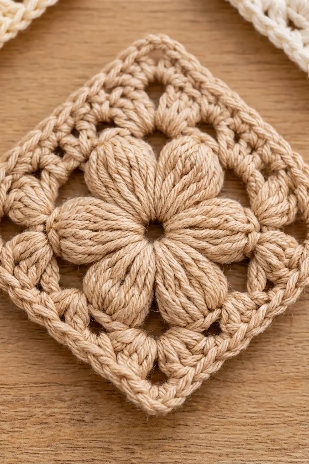 Cream-colored crocheted doily with intricate flower motifs and openwork geometric pattern on warm wooden surface.