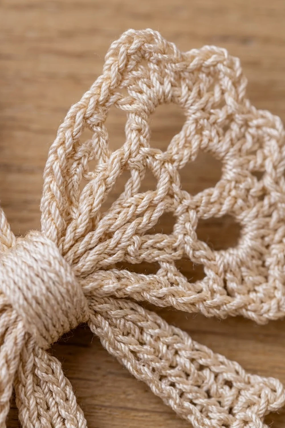 Twisted natural fiber rope in cream and tan tones coiled against a blurred wooden background.