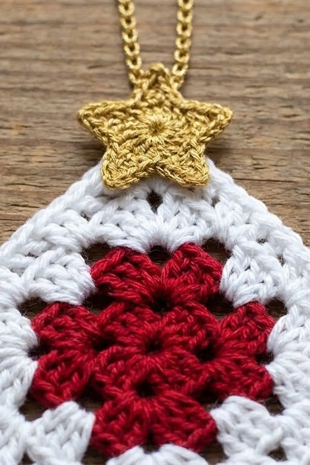 Close-up of crocheted heart ornament with gold star and chain on weathered wood.