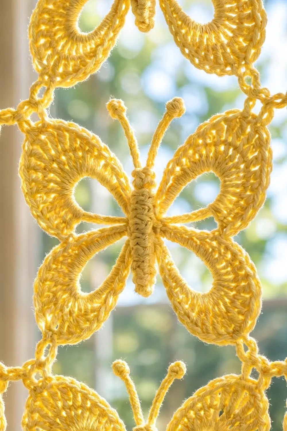 Golden crocheted lace featuring symmetrical shell-stitch motifs with textured stitching against a blurred outdoor background.