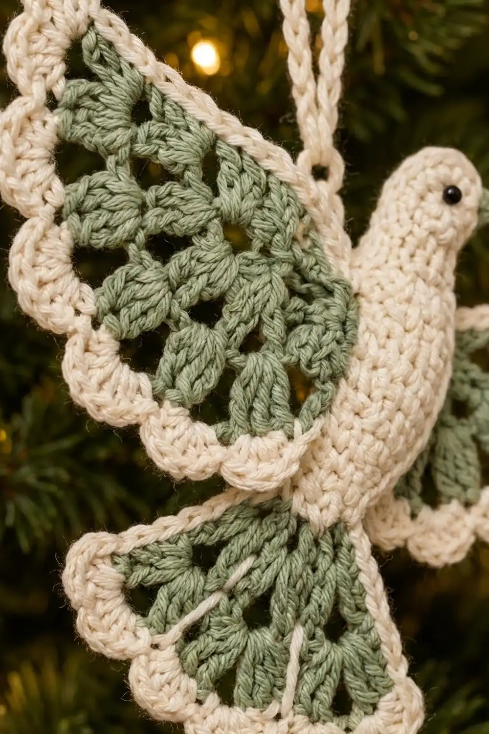 Handmade crocheted cactus with cream arms and sage green body displayed outdoors at night with warm ambient lighting.