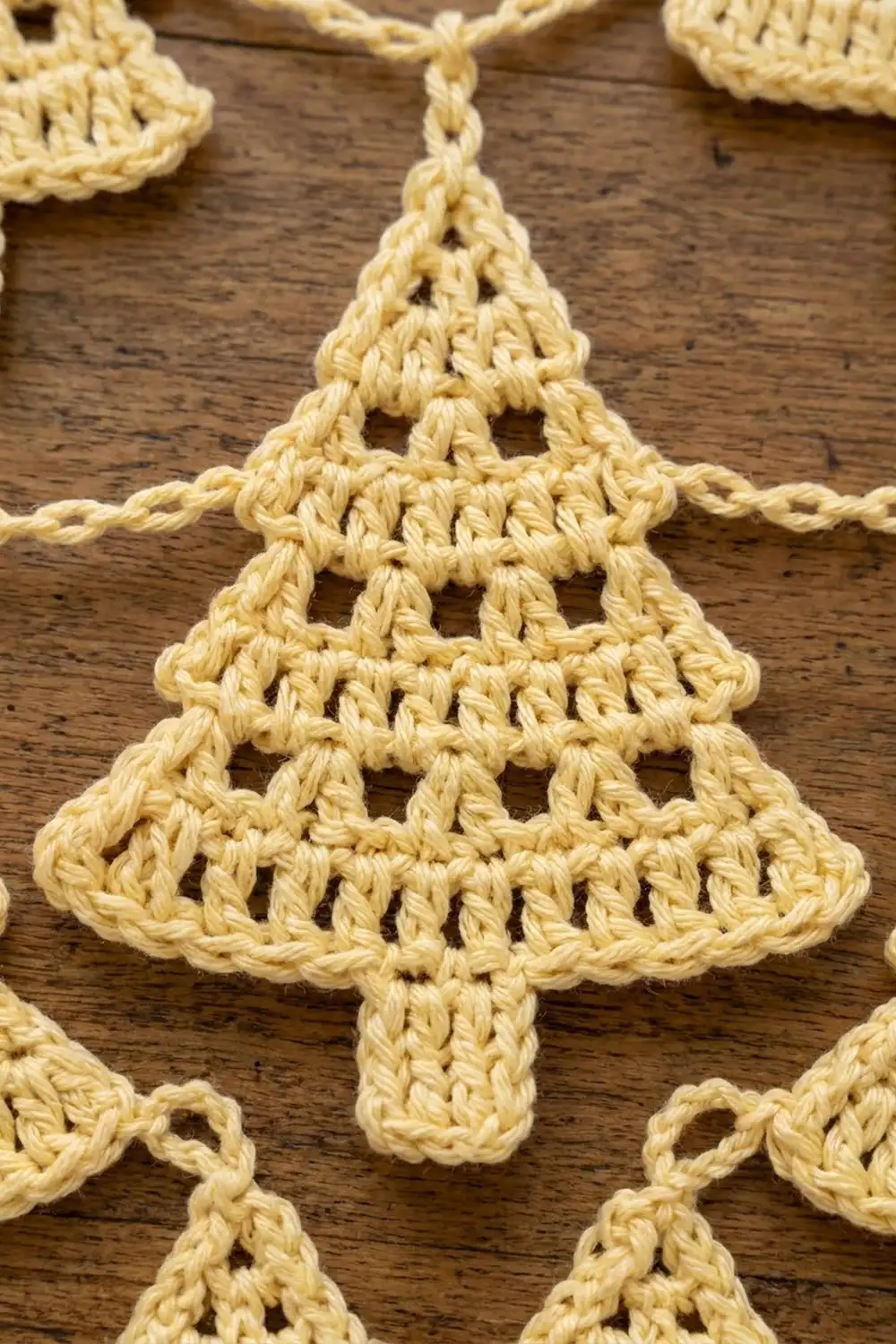 Handmade cream-colored crocheted Christmas tree decoration with delicate openwork lace hanging from twine.