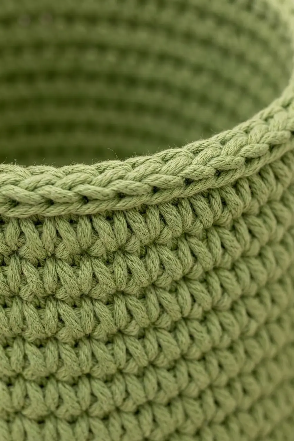 Close-up of light green crocheted fabric showing textured stitches and the bound edge border.