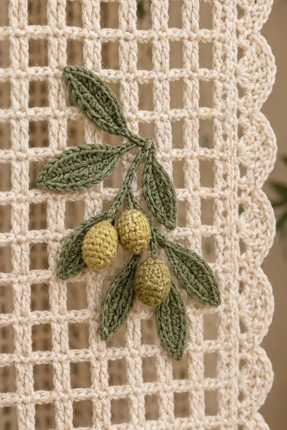 Crocheted sage green leaves with three pale yellow berries on cream waffle-textured crochet background.