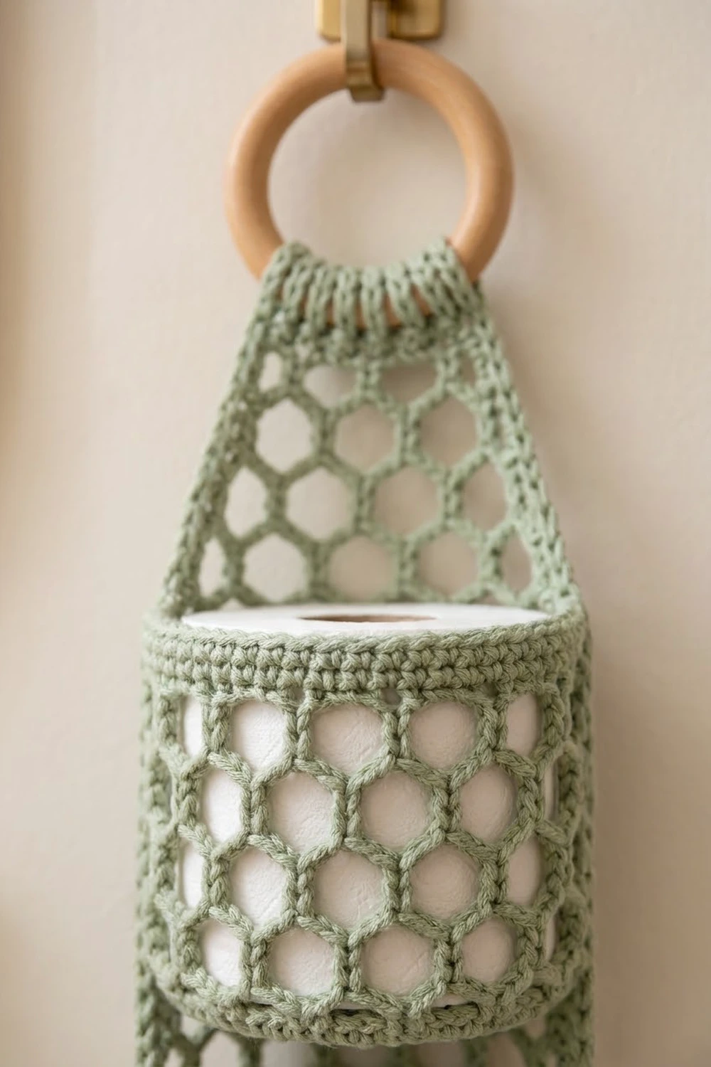 Sage-green crochet bag with hexagonal openwork pattern and natural wood handle detail against neutral background.