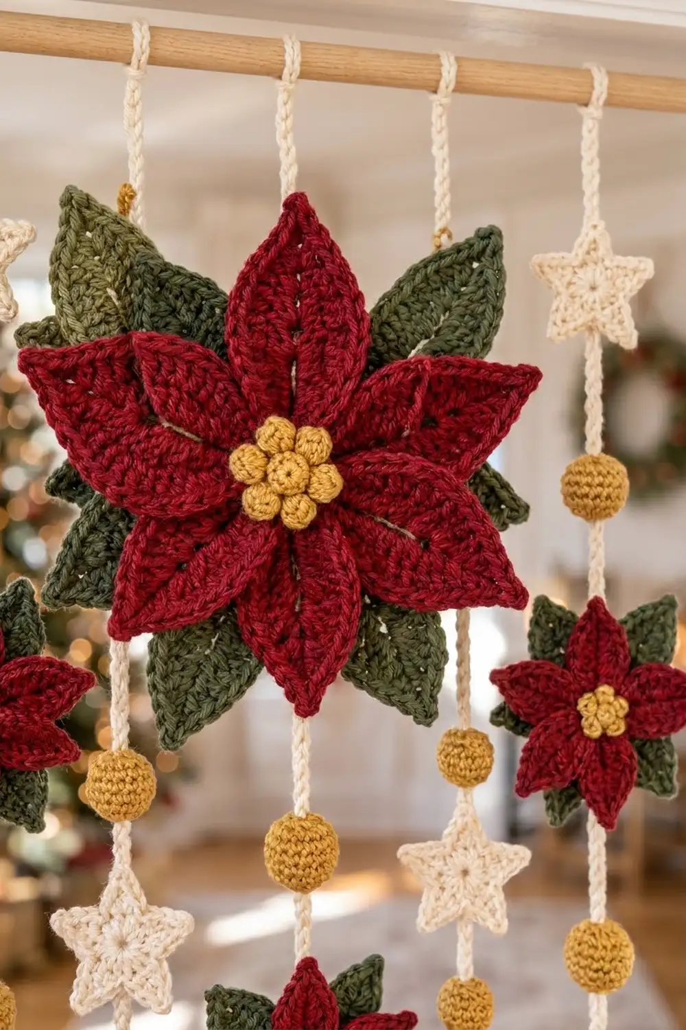 Crocheted red poinsettia with yellow center and green leaves hanging from cream-braided cord alongside star and ball ornaments.