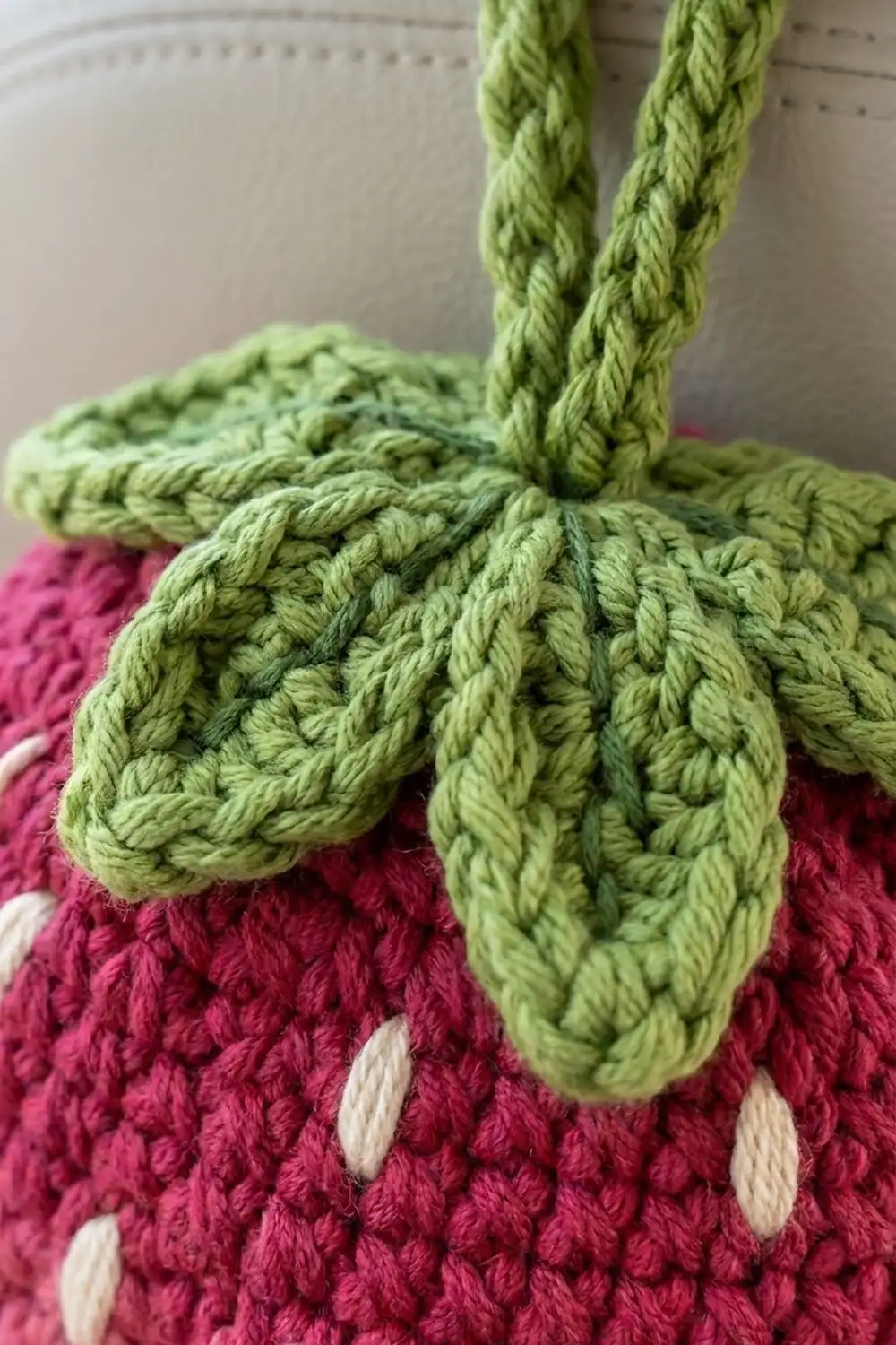 Lime-green crochet flower petals with detailed stitch texture attached to a burgundy base with white dot embellishments.